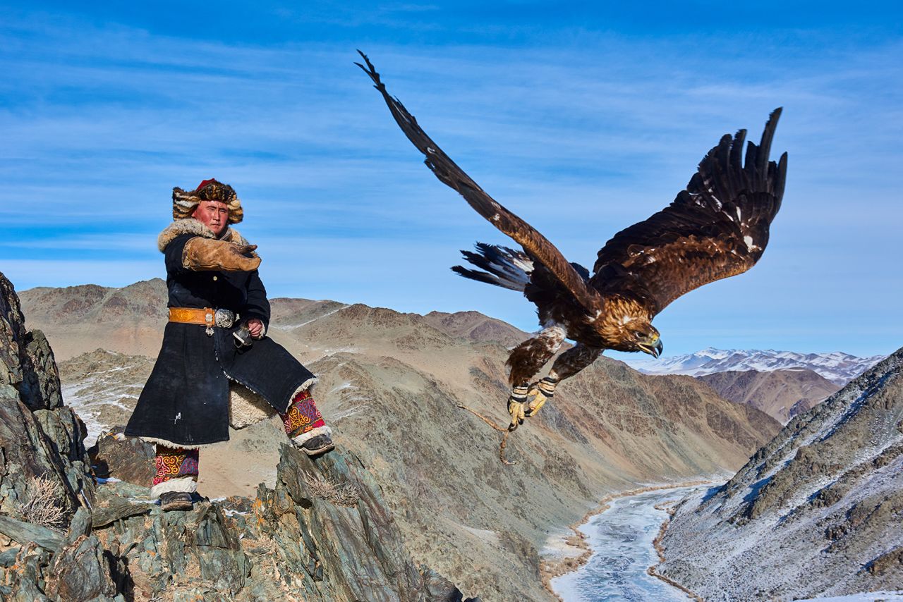 A Mongolian hunter sends his golden eagle to catch prey.